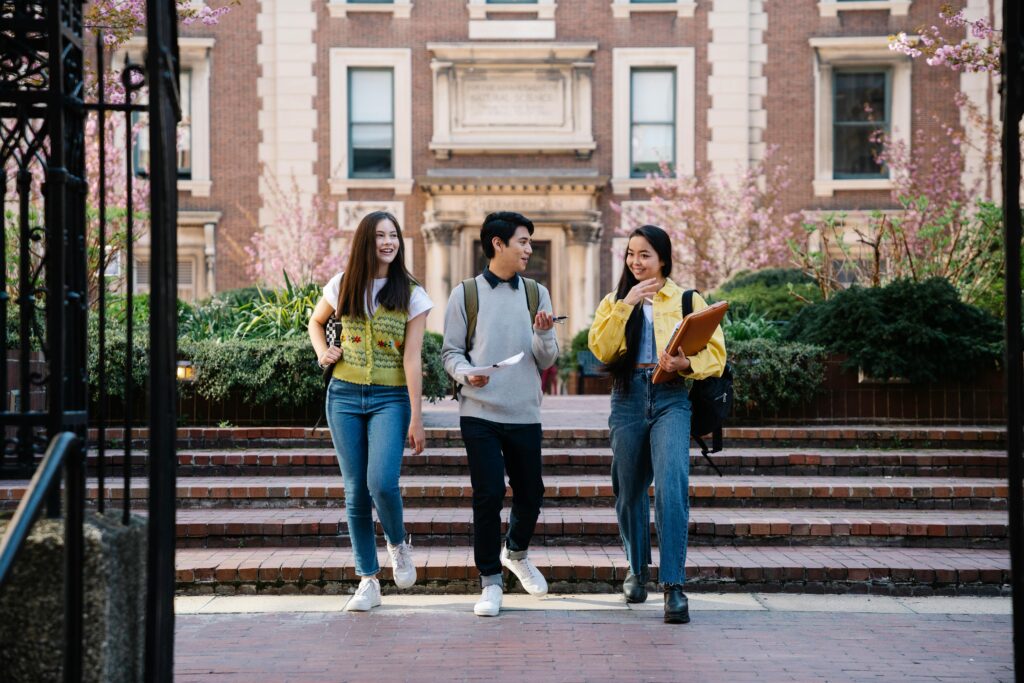 Group of students walking and talking, with a university building as the backdrop.