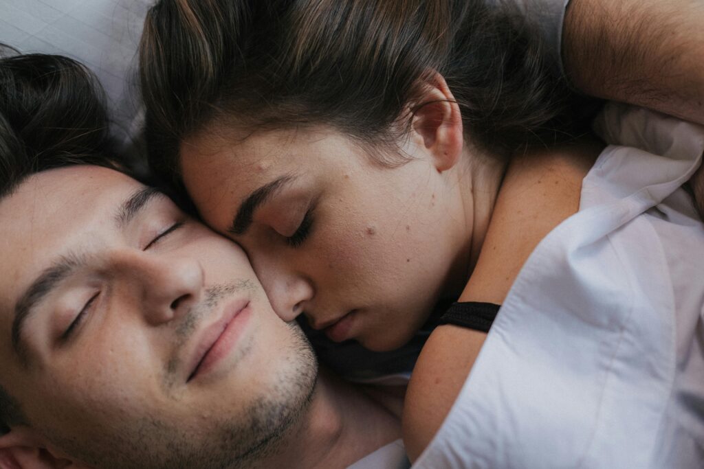 A close-up of an intimate couple cuddling and resting together in bed.